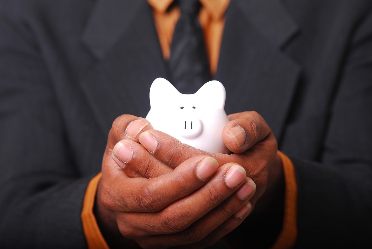 Ein Mann hält eine Sparschwein in der Hand 